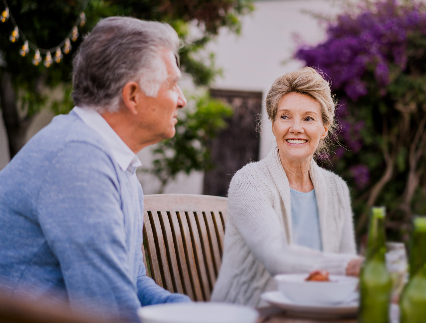 Two elderly couple drinking coffee while sitting on the bench